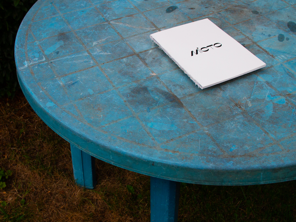 A white magazine titled Misto is lying on a blue table.